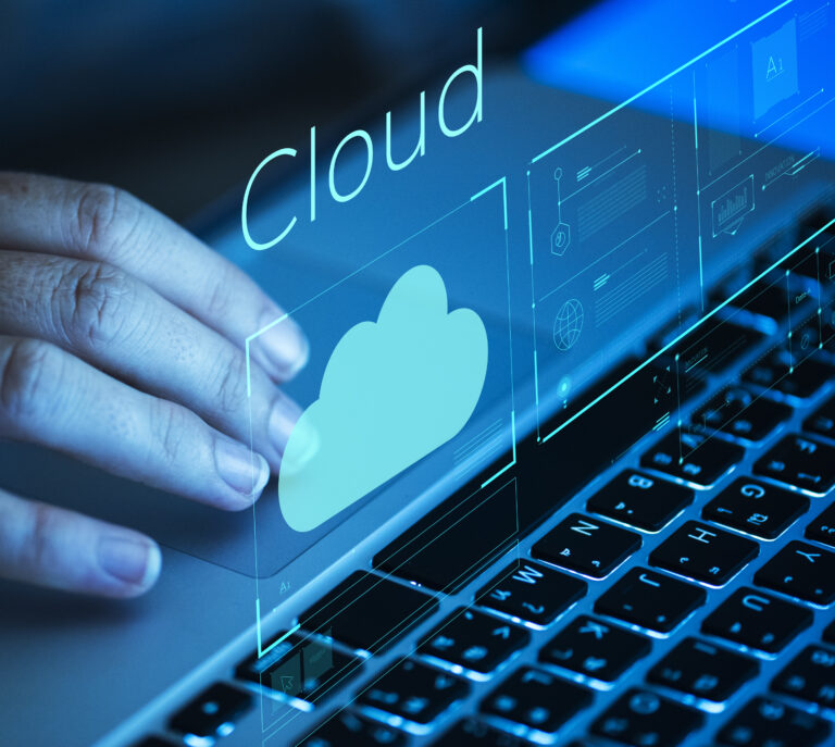 Uma mão interagindo com um laptop, com um holograma digital exibindo um ícone de nuvem (Cloud) e elementos gráficos representando a gestão de infraestrutura em nuvem, destacando a economia com Azure Reserved Instances.