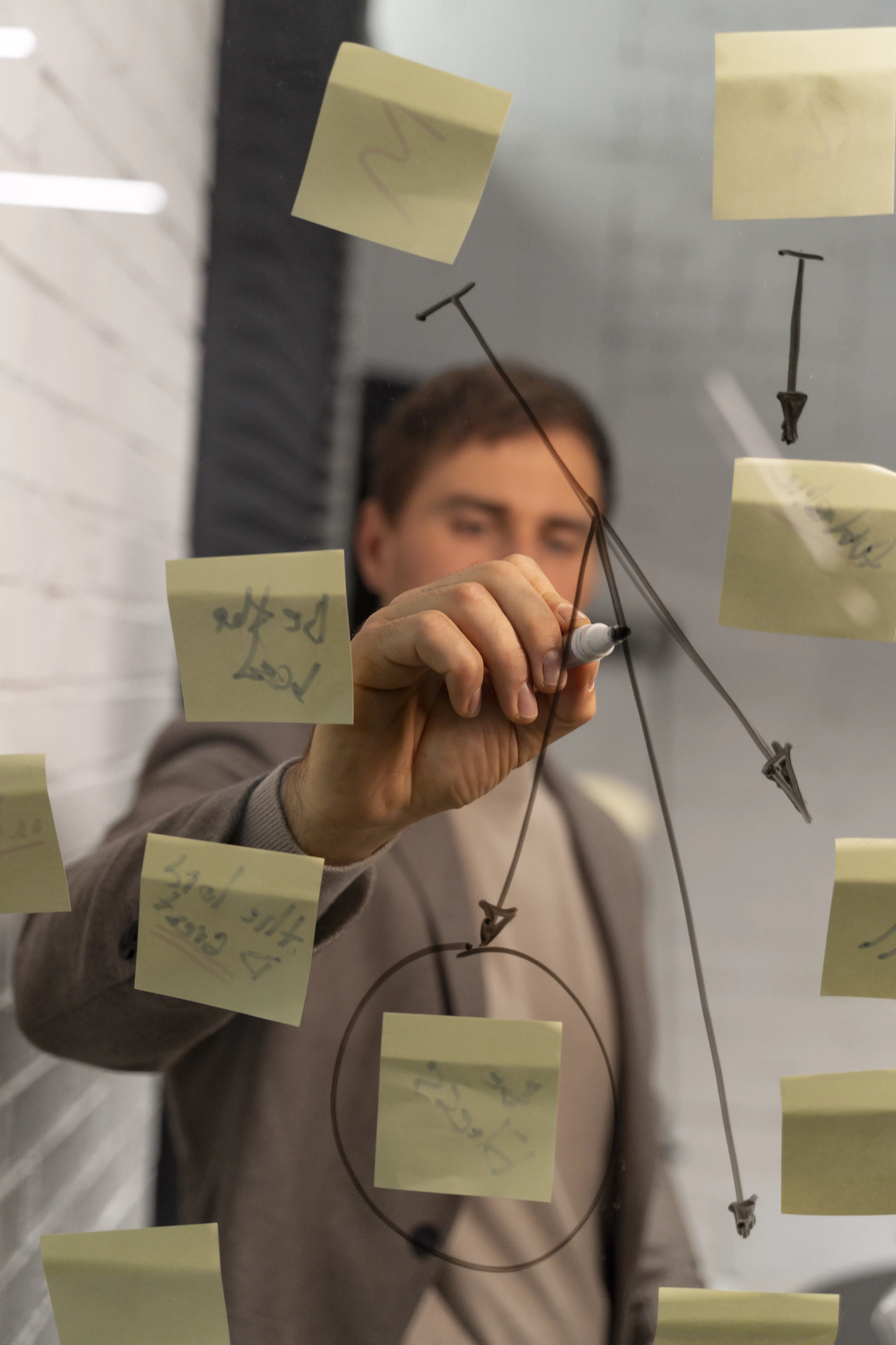 Empresário analisa processos e estrutura planos estratégicos em um quadro de vidro com post-its, visualizando iniciativas para redução de custos sem perder performance em TI.
