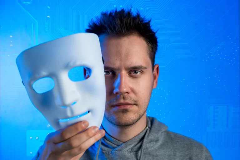 Homem segurando uma máscara branca diante do rosto, simbolizando como IA generativa e deepfakes podem ocultar a identidade real e criar versões falsas em um cenário digital azul.